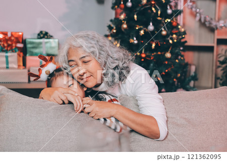 Happy family on Christmas morning. Affectionate grandmother and cheerful granddaughter open a holiday gift together at home Happy family on Christmas morning. Affectionate grandmother and cheerful granddaughter open a holiday gift together at home 121362095