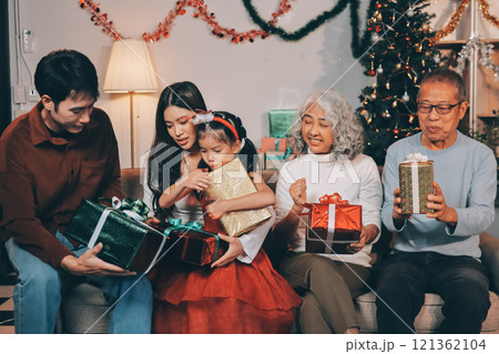 Portrait of Asian family exchanging presents during christmas at home. Attractive happy people holding gift box, celebrate holiday thanksgiving, xmas eve tradition in living room in house together. Portrait of Asian family exchanging presents during christmas at home. Attractive happy people holding gift box, celebrate holiday thanksgiving, xmas eve tradition in living room in house together. 121362104