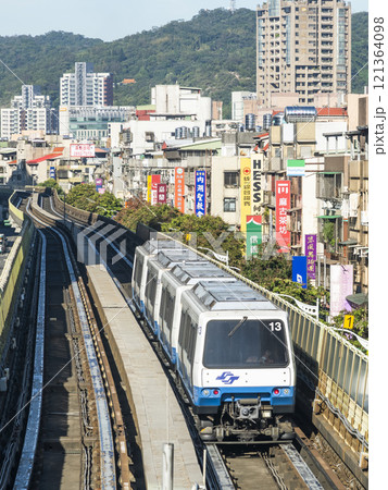 View of a Wenhu or Brown line train running on the elevated track of the Taipei Mass Rapid Transit System with the building background. View of a Wenhu or Brown line train running on the elevated track of the Taipei Mass Rapid Transit System with the building background. 121364098