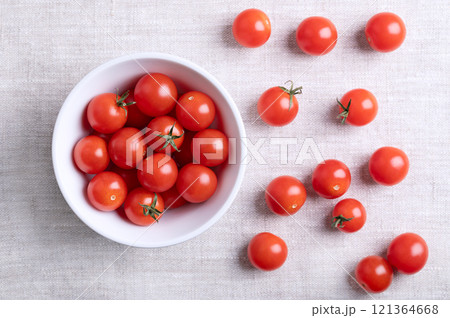 Small red cherry tomatoes in a white bowl on linen fabric, from above. Fresh, ripe, tiny and round cocktail tomatoes of the type Solanum lycopersicum var. cerasiforme, of juicy and sweet taste. Small red cherry tomatoes in a white bowl on linen fabric, from above. Fresh, ripe, tiny and round cocktail tomatoes of the type Solanum lycopersicum var. cerasiforme, of juicy and sweet taste. 121364668