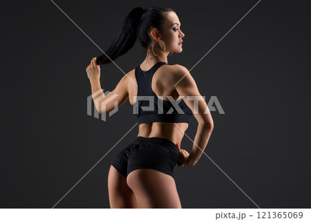 Tanned brunette doing fitness rearview against gray background 121365069