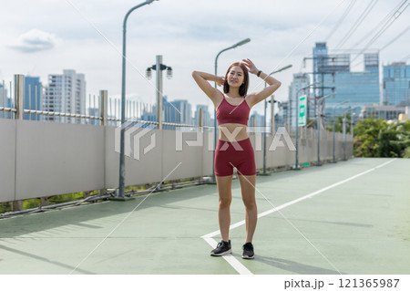 Young beautiful woman sportswear workout clothes exercise in street city park before morning run. Asian strong female sporty sportswear stretching outdoors. fitness healthy concept. 121365987