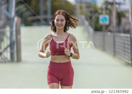 Young beautiful woman sportswear workout clothes wear headphone exercise running in street city before morning run. Asian strong female sporty sportswear jogging outdoors. fitness healthy concept. Young beautiful woman sportswear workout clothes wear headphone exercise running in street city before morning run. Asian strong female sporty sportswear jogging outdoors. fitness healthy concept. 121365992