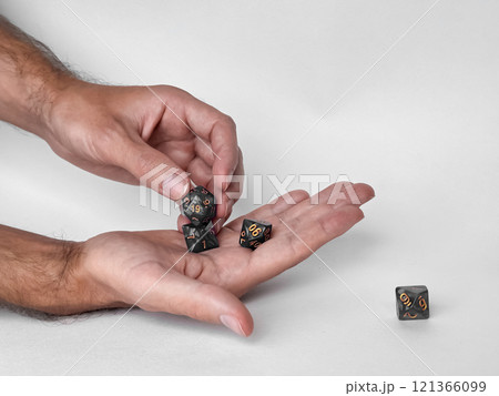 Hands holding polyhedral dice for dungeons and dragons game session 121366099