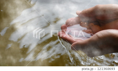 湯けむりが立つ檜の露天風呂に入浴する男性が湯を手ですくうシーン 湯けむりが立つ檜の露天風呂に入浴する男性が湯を手ですくうシーン 121368693