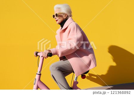 Smiling happy cool gray haired old senior woman on scooter or bicycle In a pink coat Smiling happy cool gray haired old senior woman on scooter or bicycle In a pink coat 121368892