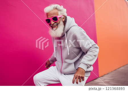 stylish elderly cool gray haired bearded hipster man in pink sunglasses walks outdoors on pink background 121368893