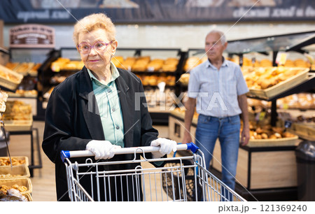 Older european woman with glasses shopping in bread section of supermarket 121369240