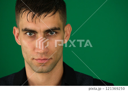 Portrait of young businessman with hands in pockets standing isolated against green background Portrait of young businessman with hands in pockets standing isolated against green background 121369250