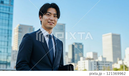 現代の都市風景でビジネスバッグを持つスーツ姿の若い日本人ビジネスマン 121369962