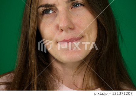 Thoughtful Asian woman keeps hand on chin looks pensively above dressed in casual blue jumper poses against brown background blank copy space for your advertising content thinks about future 121371207
