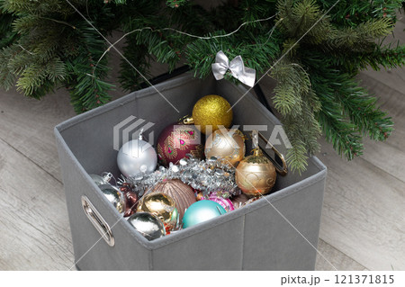 a box of Christmas decorations near a decorated Christmas tree 121371815