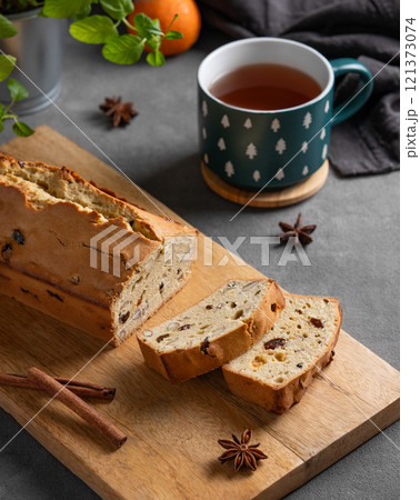 Spicy pie with fruits, nuts and spices on a wooden board, on a dark background 121373074
