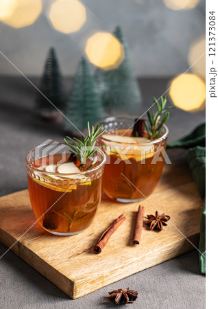 Homemade apple punch with fresh apples, cinnamon and rosemary in a two cups on a wooden board 121373084