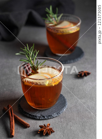 Homemade apple punch with fresh apples, cinnamon and rosemary in a two cups on a dark background Homemade apple punch with fresh apples, cinnamon and rosemary in a two cups on a dark background 121373085