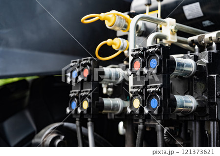 Close-up of hydraulic connectors and valves on industrial equipment. 121373621