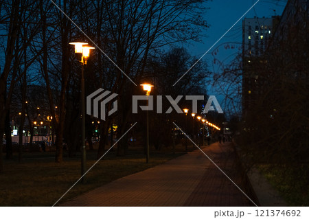 A pedestrian path illuminated by lanterns in the evening, in December A pedestrian path illuminated by lanterns in the evening, in December 121374692