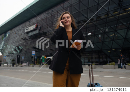 Smiling female business professional hailing taxi. Happy businesswoman waiting for taxi on the city street. 121374911
