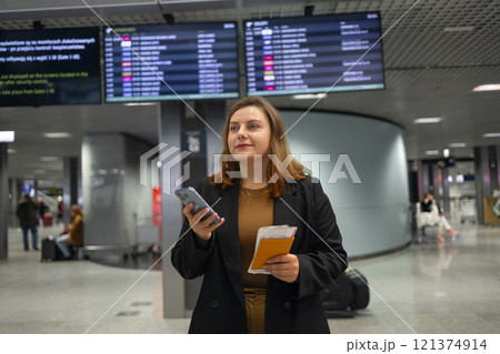 Portrait of positive cheerful traveler woman hold ticket ready enjoy voyage tour passenger walk in airport terminal to boarding gate. Attractive beautiful female tourist excited to go travel abroad by 121374914