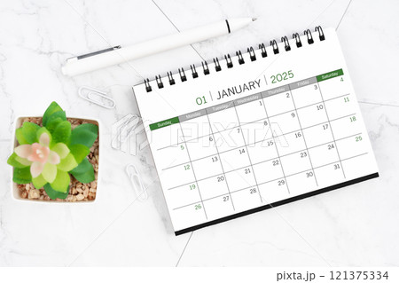 Desk calendar on month of January 2025 with pen on white marble background. Desk calendar on month of January 2025 with pen on white marble background. 121375334
