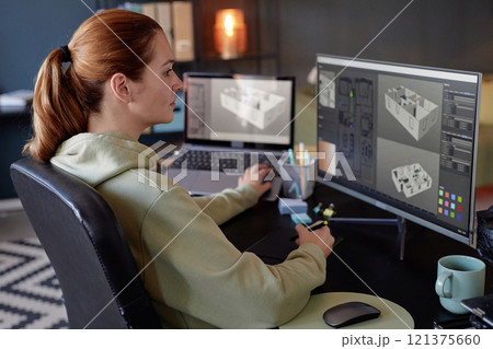 Someone focused on creating 3D models on professional computer setup in an office workspace equipped with multiple screens and other desk accessories Someone focused on creating 3D models on professional computer setup in an office workspace equipped with multiple screens and other desk accessories 121375660