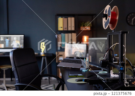 Workspace showcasing advanced 3D printer amidst contemporary office setting. Monitor displaying design software and various organizational tools highlighting productive environment Workspace showcasing advanced 3D printer amidst contemporary office setting. Monitor displaying design software and various organizational tools highlighting productive environment 121375676