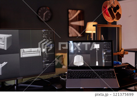 Workspace featuring computer screens displaying 3D designs for furniture, showing advanced modeling software with a 3D printer in background creating intricate objects 121375699