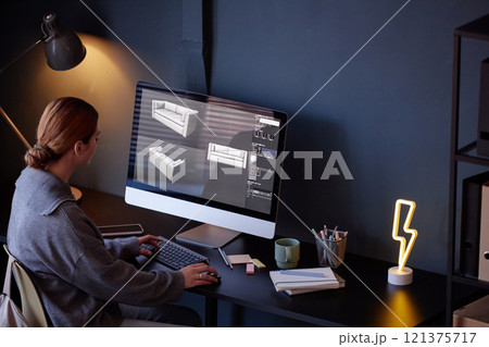 Person working on computer, designing modern furniture pieces with 3D software. Room includes a desk lamp, small plants, and a lightning-shaped light creating cozy atmosphere Person working on computer, designing modern furniture pieces with 3D software. Room includes a desk lamp, small plants, and a lightning-shaped light creating cozy atmosphere 121375717