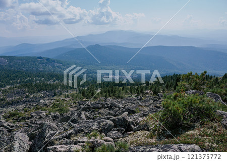 Vast Siberian taiga with hills stretching beyond the horizon. Stones and coniferous trees. Summer natural landscape 121375772
