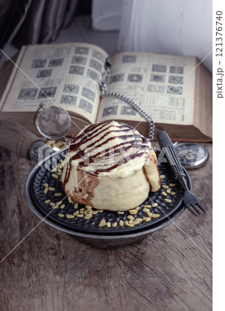 Cinnamon roll topped with rich cream cheese frosting served with Metal fork on old rustic wooden background. 121376740