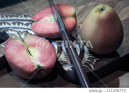 Fresh kissabel apple fruit and Cut the apple in each half with knife on wooden cutting board. Fresh kissabel apple fruit and Cut the apple in each half with knife on wooden cutting board. 121376773