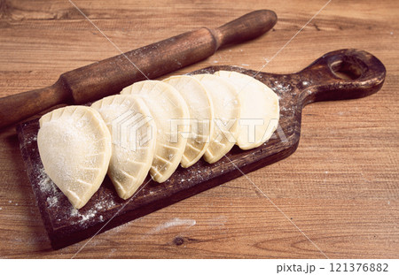 raw chebureks, mini, on a cutting board, wooden table, close-up, no people, 121376882