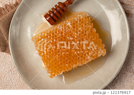 honeycomb, with a wooden spoon-spindle, on a plate, no people, 121376917