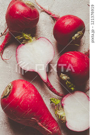 Freshly harvested red radishes displayed on a neutral surface highlighting their vibrant color and crisp texture 121376919