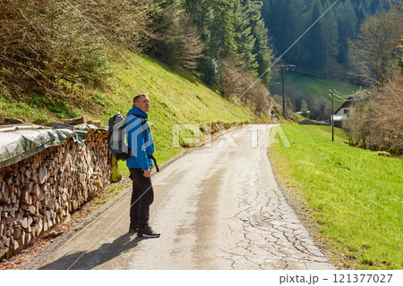 Man hiking at sunset mountains with heavy backpack Travel Lifestyle wanderlust adventure concept summer vacations outdoor alone into the wild. Hipster man traveler wanderer wearing travelling alone 121377027