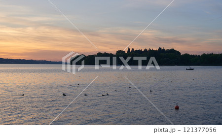 Serene Pier at Sunset with Sailboats on Calm Lake: Captivating Evening Scene with Orange and Pink Sky Reflections in Tranquil Marina 121377056