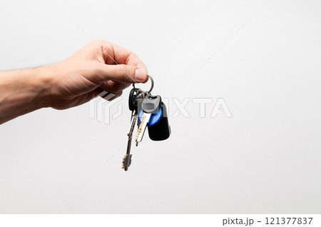 Salesman businessman holding keys, advertising sale, services or purchase of real estate. close-up on gray background Salesman businessman holding keys, advertising sale, services or purchase of real estate. close-up on gray background 121377837