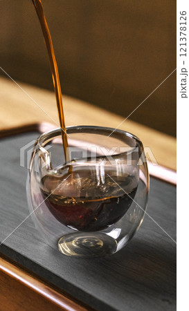An artisancrafted coffee is elegantly poured into a sleek clear glass container 121378126
