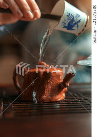 Pouring water carefully into a beautiful, miniature teapot creates a tranquil, cozy moment 121378280