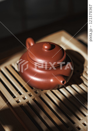 An Elegant Clay Teapot beautifully placed on a stylish Wooden Tea Tray for serving tea 121378367