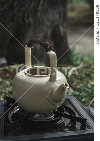 An Elegant Teapot Set on a Stove amidst a Beautiful Natural Setting in the Outdoors 121378368