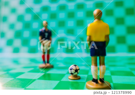 Soccer strategy concept with miniature referee and players on checkered field, tactical game setup 121378990