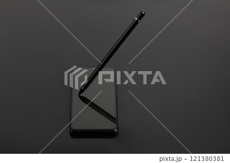 Stylus for drawing on capacitive screens. The stylus lies on the smartphone screen on a black background. 121380381