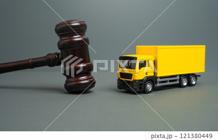 Yellow truck and judge's gavel. Court case. New laws and acts. Restrictions and regulations. Bankruptcy. Sale of assets of a transport company through auction. 121380449