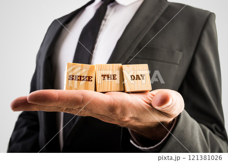 Businessman holding wooden cubes in the palm of his hand with the words Seize the day 121381026