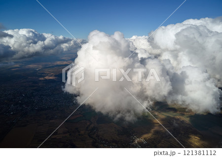 Aerial view from airplane window at high altitude of earth covered with white puffy cumulus clouds 121381112