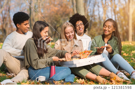 Hungry international students having picnic outdoors, grabbing pizza slices and smiling Hungry international students having picnic outdoors, grabbing pizza slices and smiling 121381598