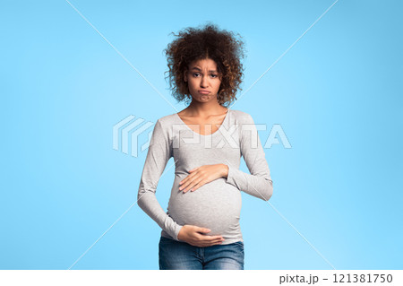 Hormones and mood changes. Sad expectant woman touching belly over grey studio background Hormones and mood changes. Sad expectant woman touching belly over grey studio background 121381750