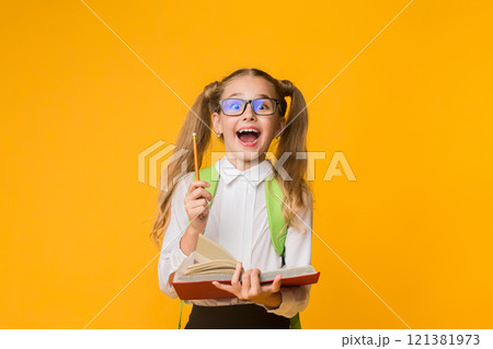 School Education And Knowledge. Overjoyed Elementary Student Girl Holding Opened Book And Pencil On Yellow Background. Empty Space 121381973