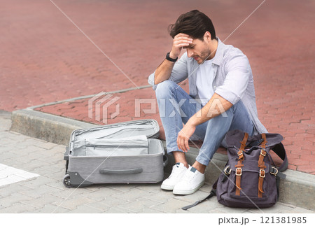 Lost luggage. Desperate traveler sitting at international airport with empty suitcase, free space 121381985